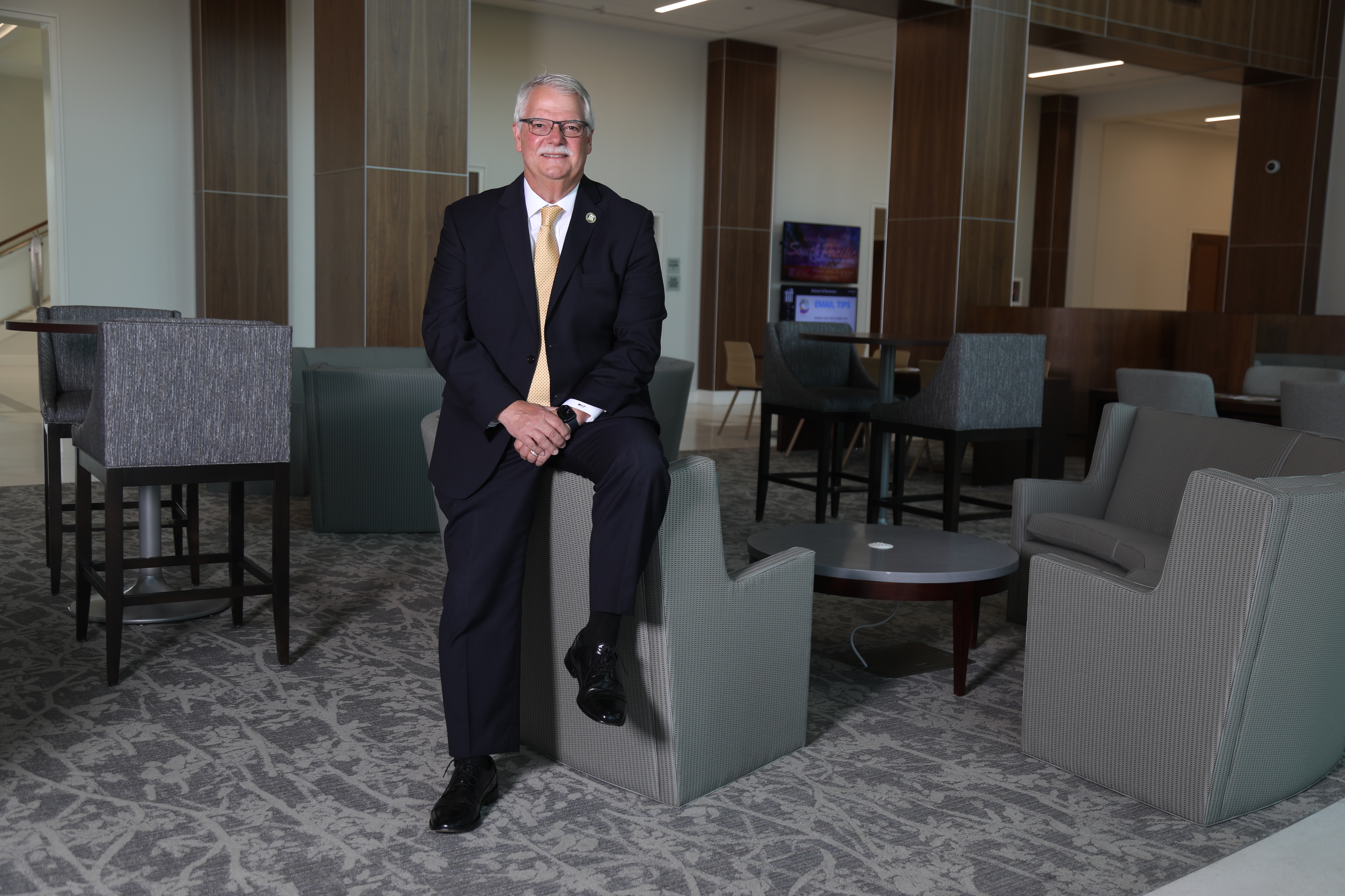 Dr. Stewart Thomas posing for picture sitting on the edge of a chair