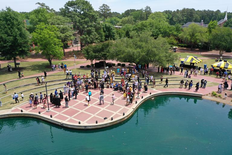 Drone image of people gathered in the amphatheatre, next to the water feature, on the quad of UNC Pembroke.