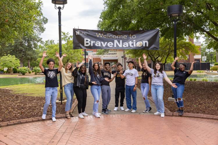 students at UNCP in front of banner cheering