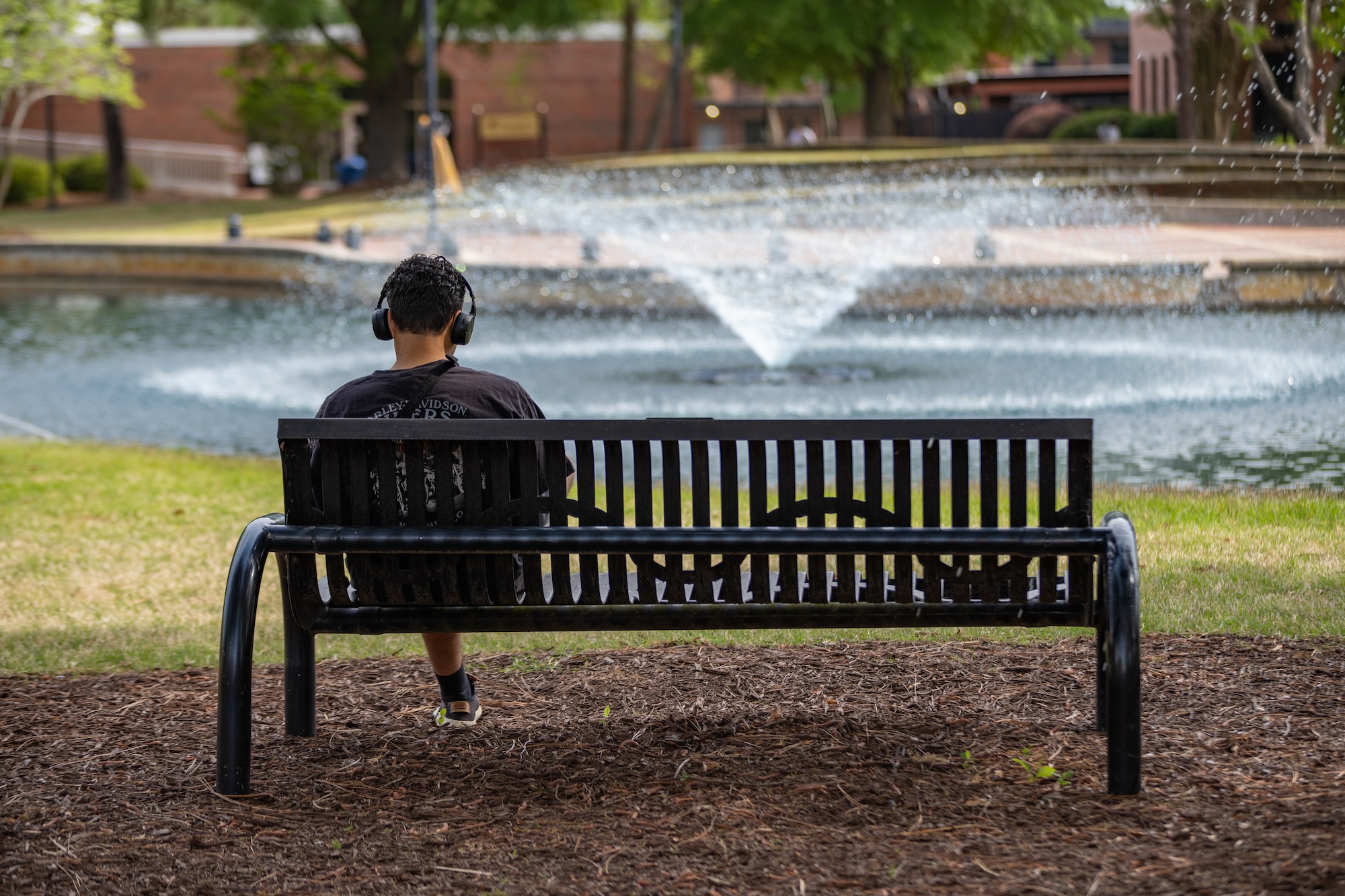 A person sitting on a bench near the UNCP water feature