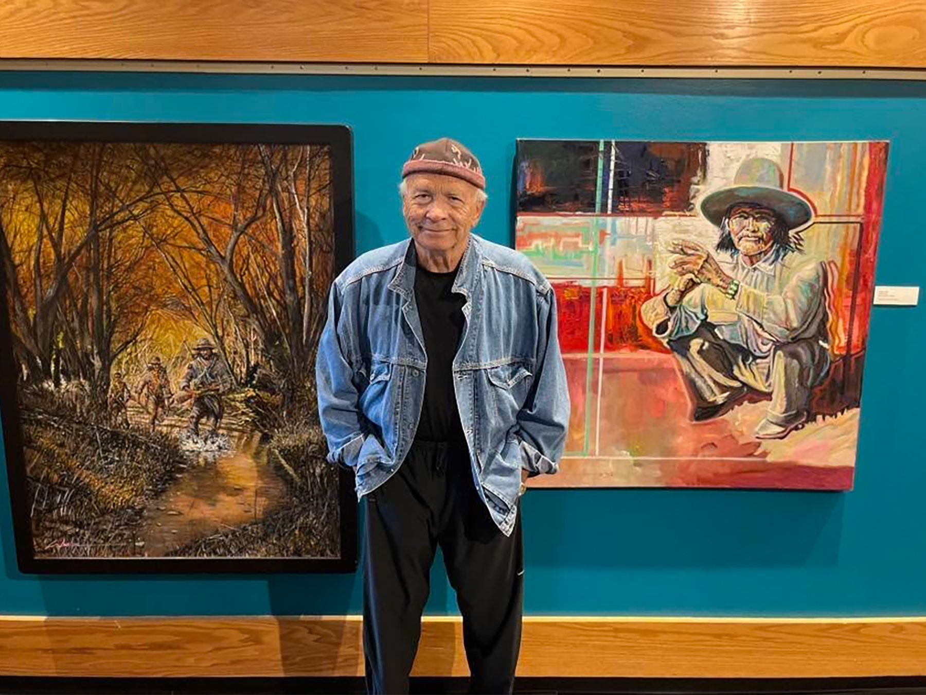 Gene Lockear stands before two of his paintings.