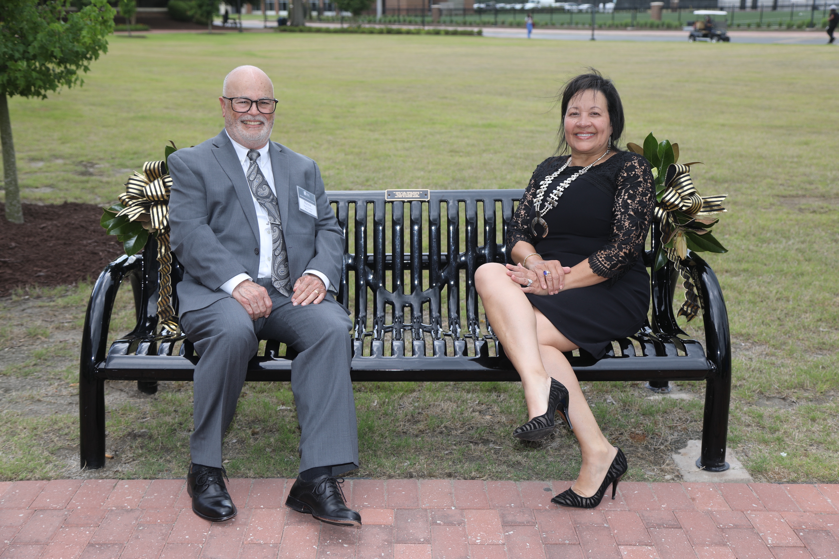 Ron Oxendine and his wife, Tina sit on a bench dedicated to their parents. 