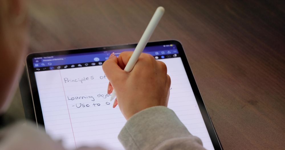 Female UNCP student using a tablet to write with a stylus as if on notebook paper.