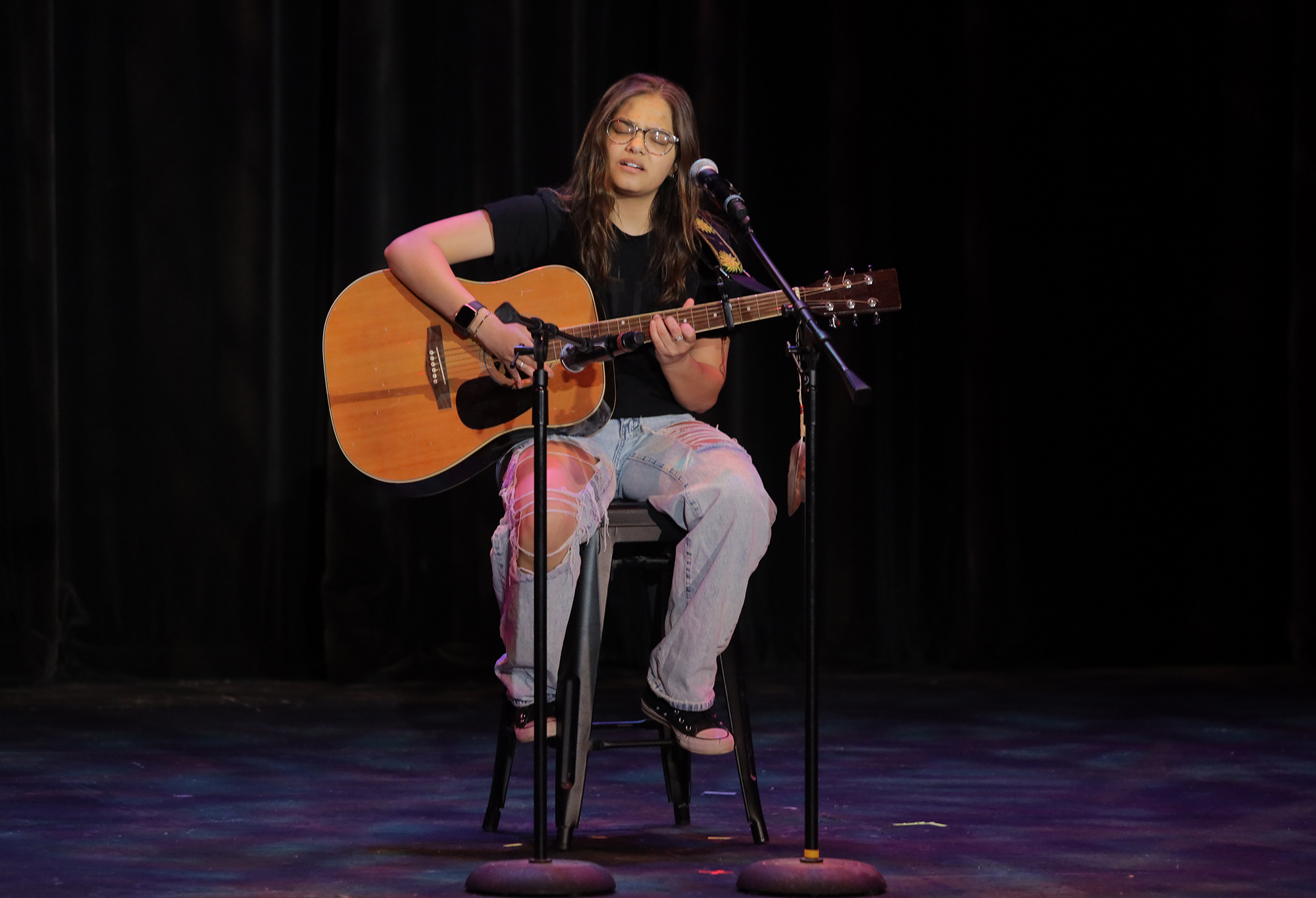 a performer plays guitar and sings on the gpac stage