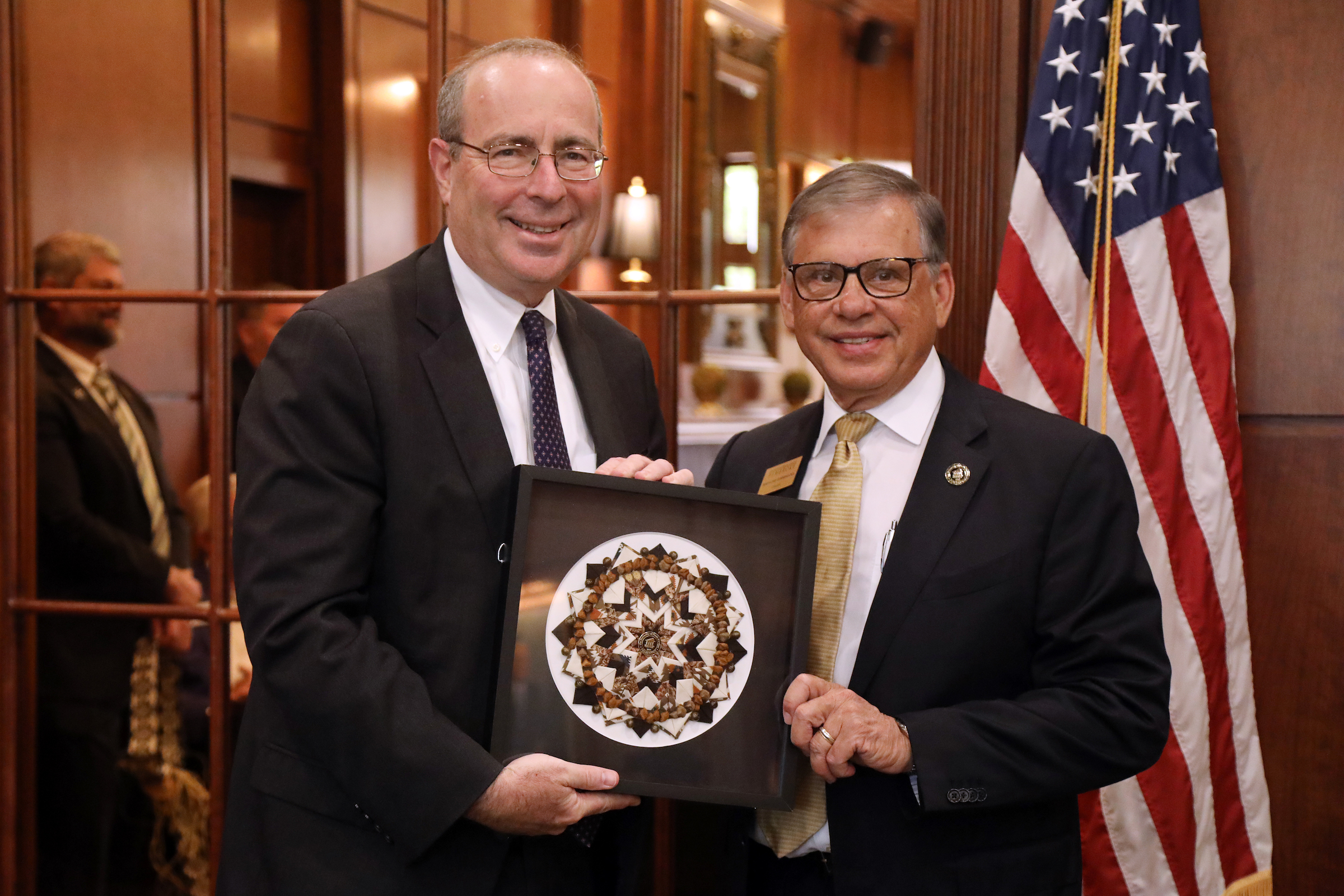 Chancellor Robin Gary Cummings (right) presents Federal Reserve Bank of Richmond President Tom Barkin with a Lumbee pinecone patchwork artwork during his visit to UNCP