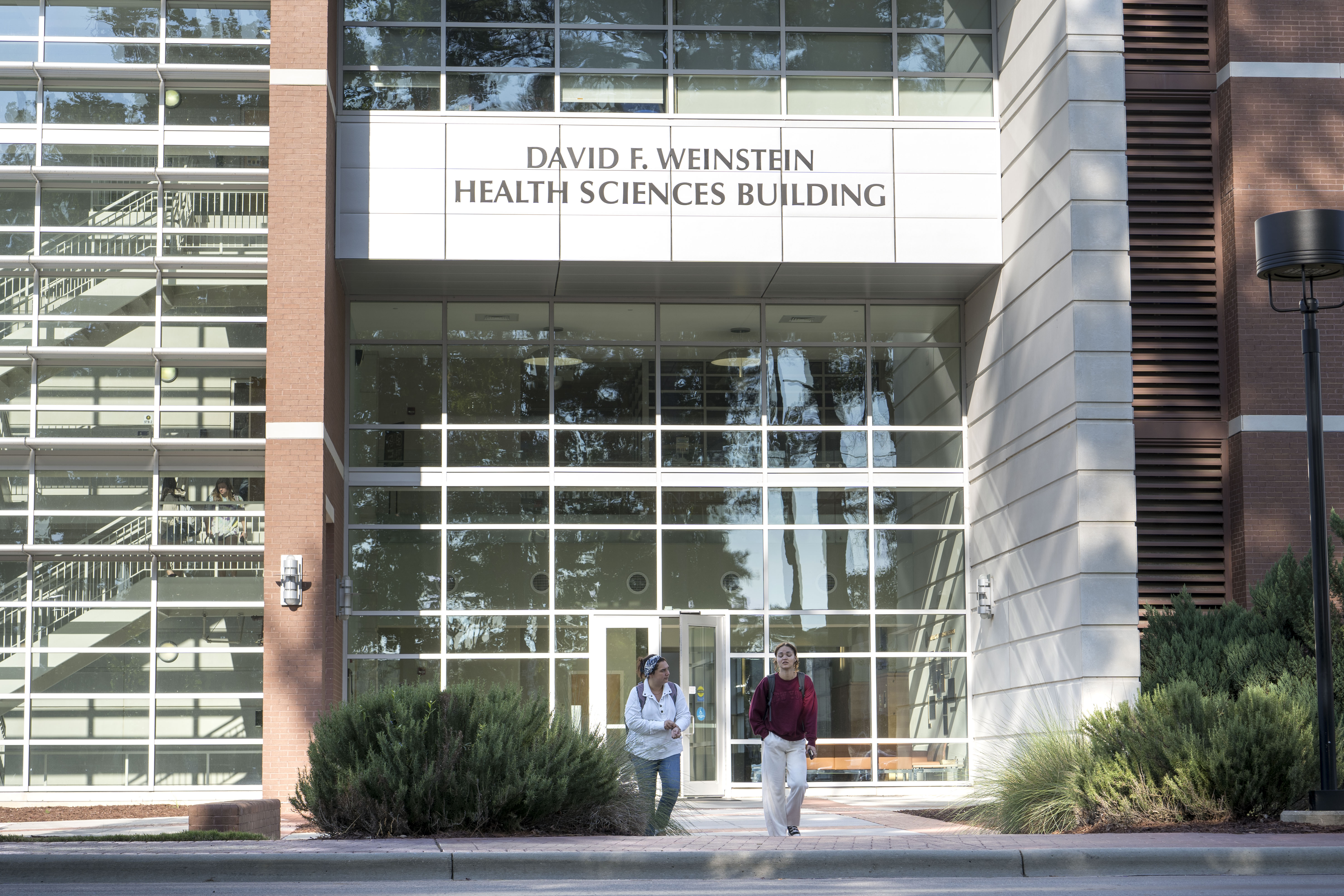 Students walking out of the doors of the Weinstein Health Sciences building on the UNCP campus