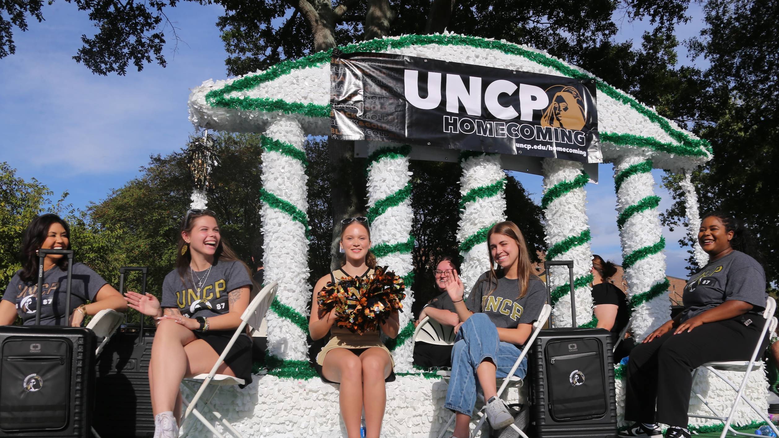 students wave from a float during the homecoming parade