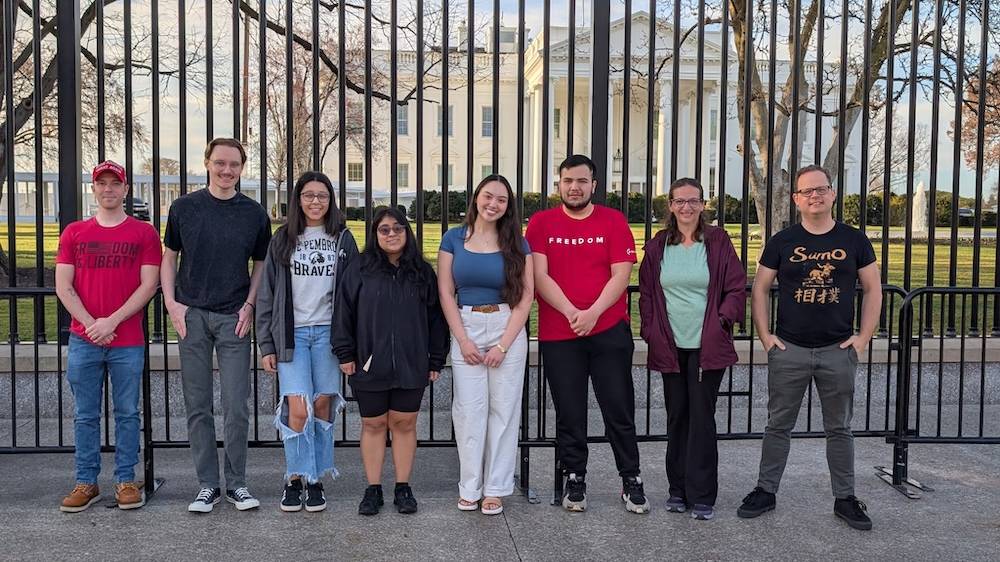 Students on Study Away trip pose in front of fence in the front of the White House in DC