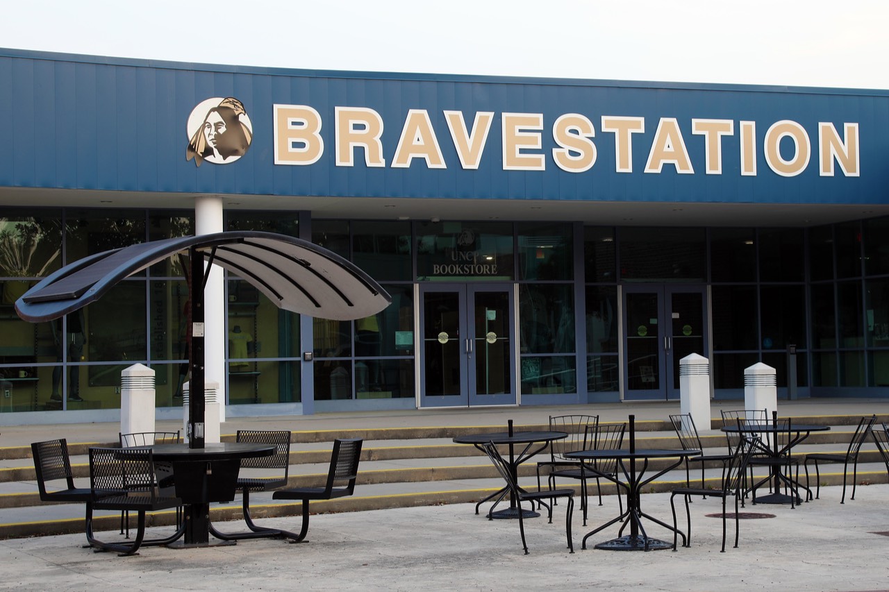 The BRAVESTATION entrance at the UNCP campus bookstore, with outdoor seating and a solar-powered charging table with a curved canopy.