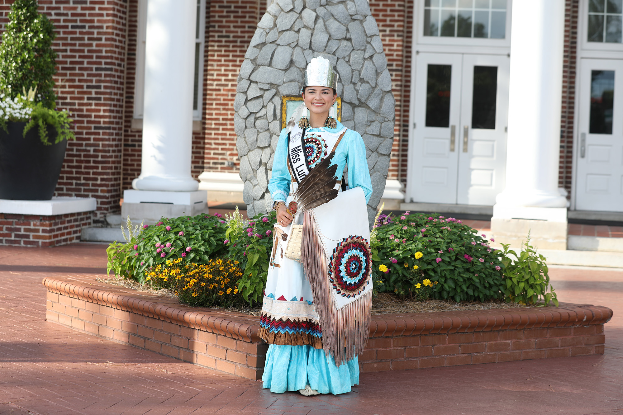 Miss Lumbee, Taylor Davis, stands before the arrowhead statue in front of Old Main.