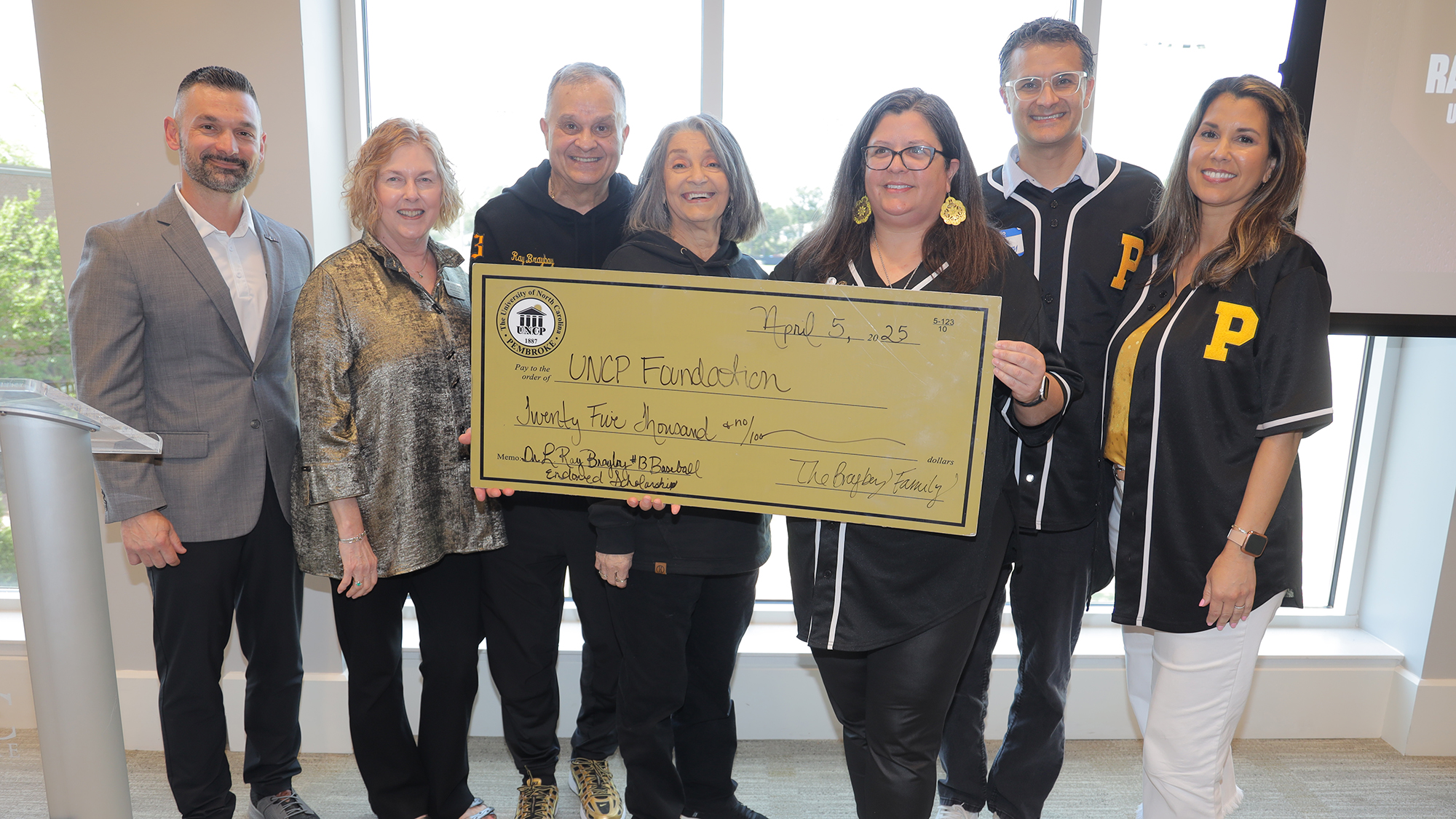 group from athletics holding an over-sized check
