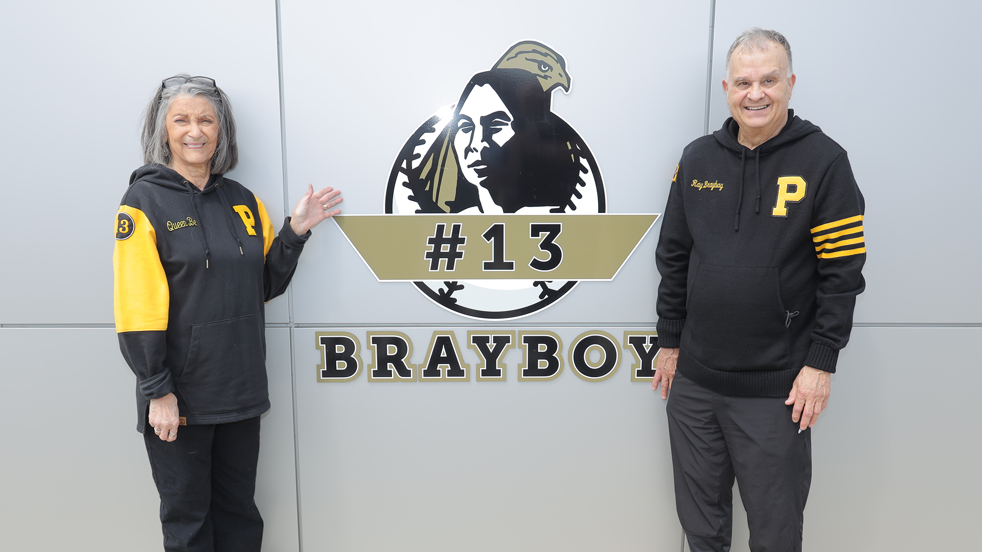 Ray Brayboy and his wife pose in front of retired jersey number on wall
