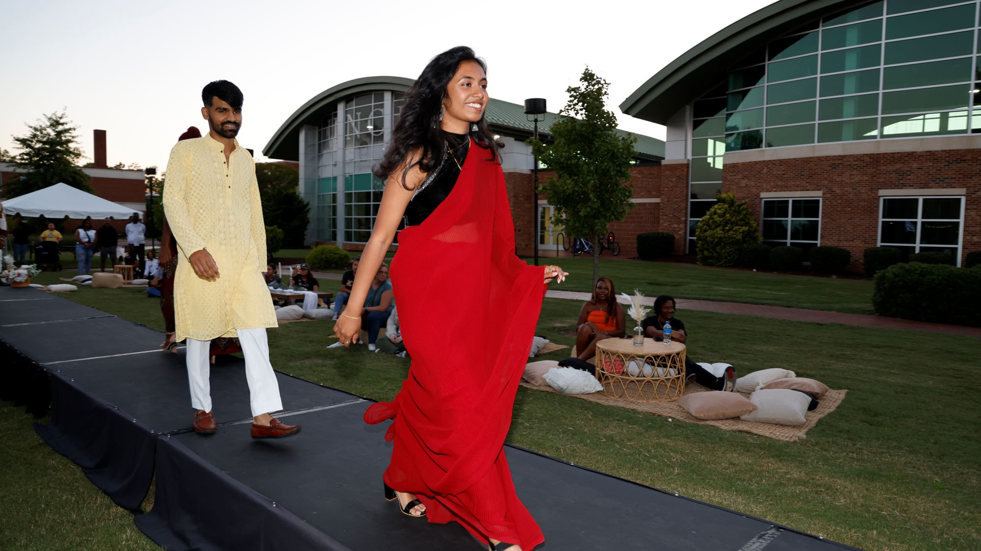 UNCP international students walk the stage in traditional attire at the OGE cultural fashion show.