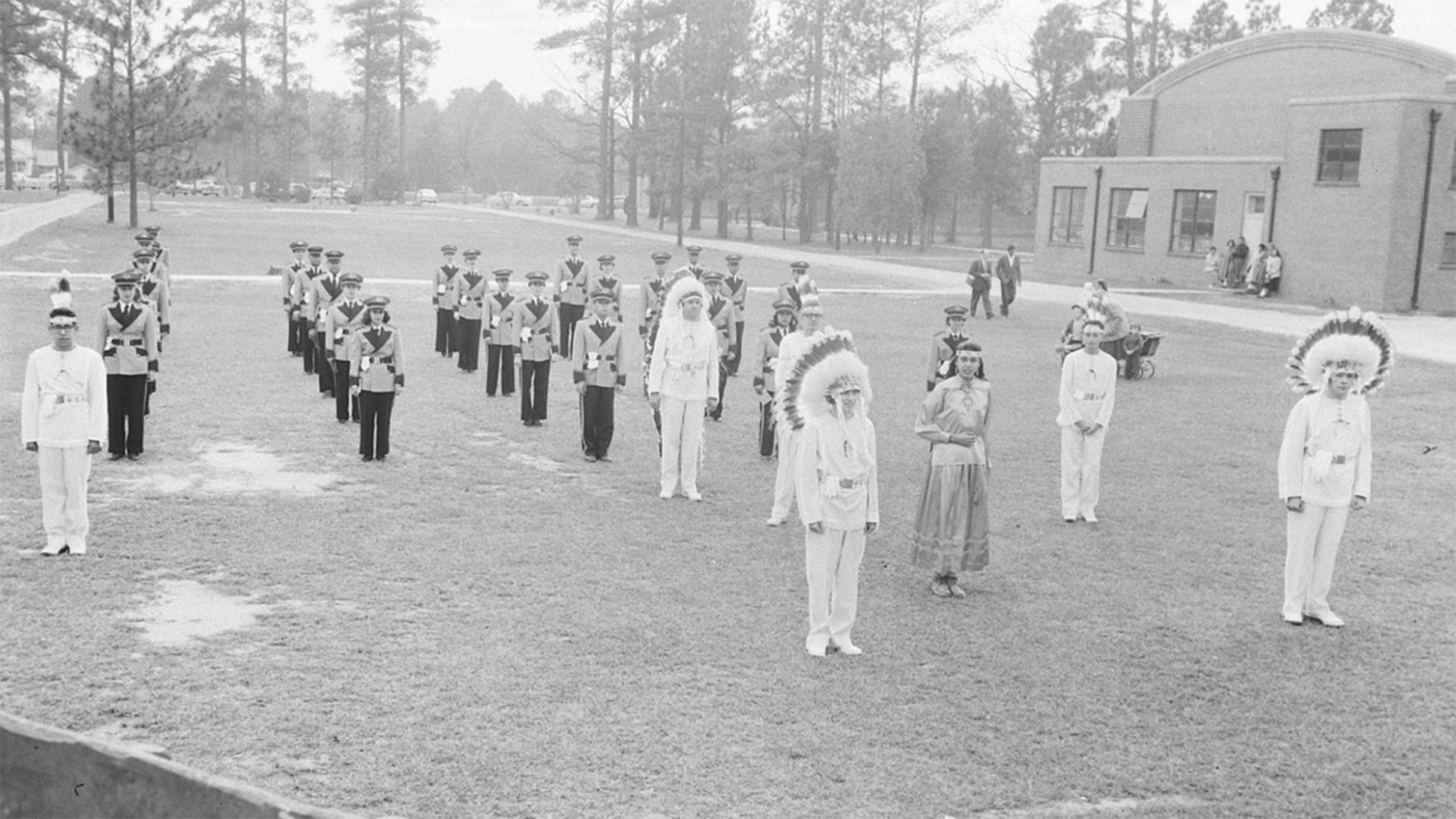 marching band in ranks on the field in uniform including feathered headdresses