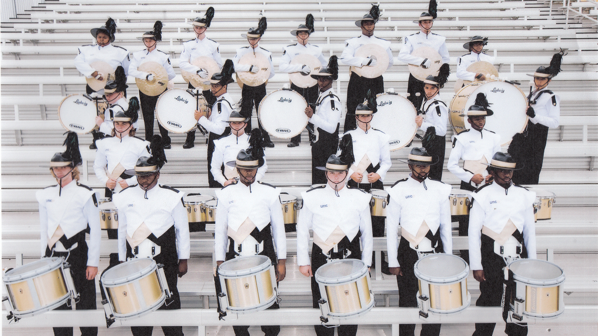 drumline players lined up in bleachers for photo