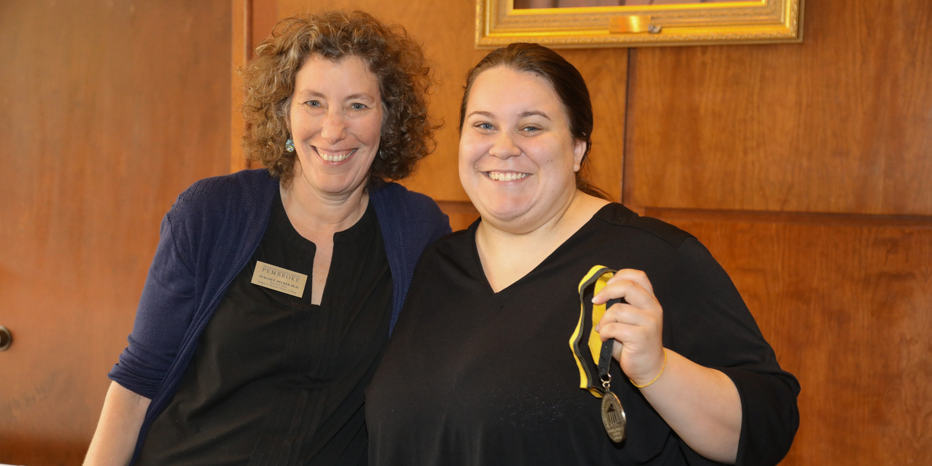 Honors College leadership with a student receiving her honors medalion at a luncheon.