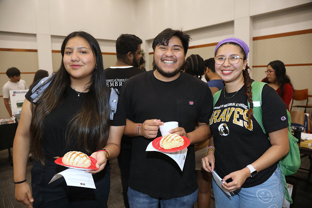 Three hispanic students smiling at the camera during a Festival of Cultures at UNC Pembroke.