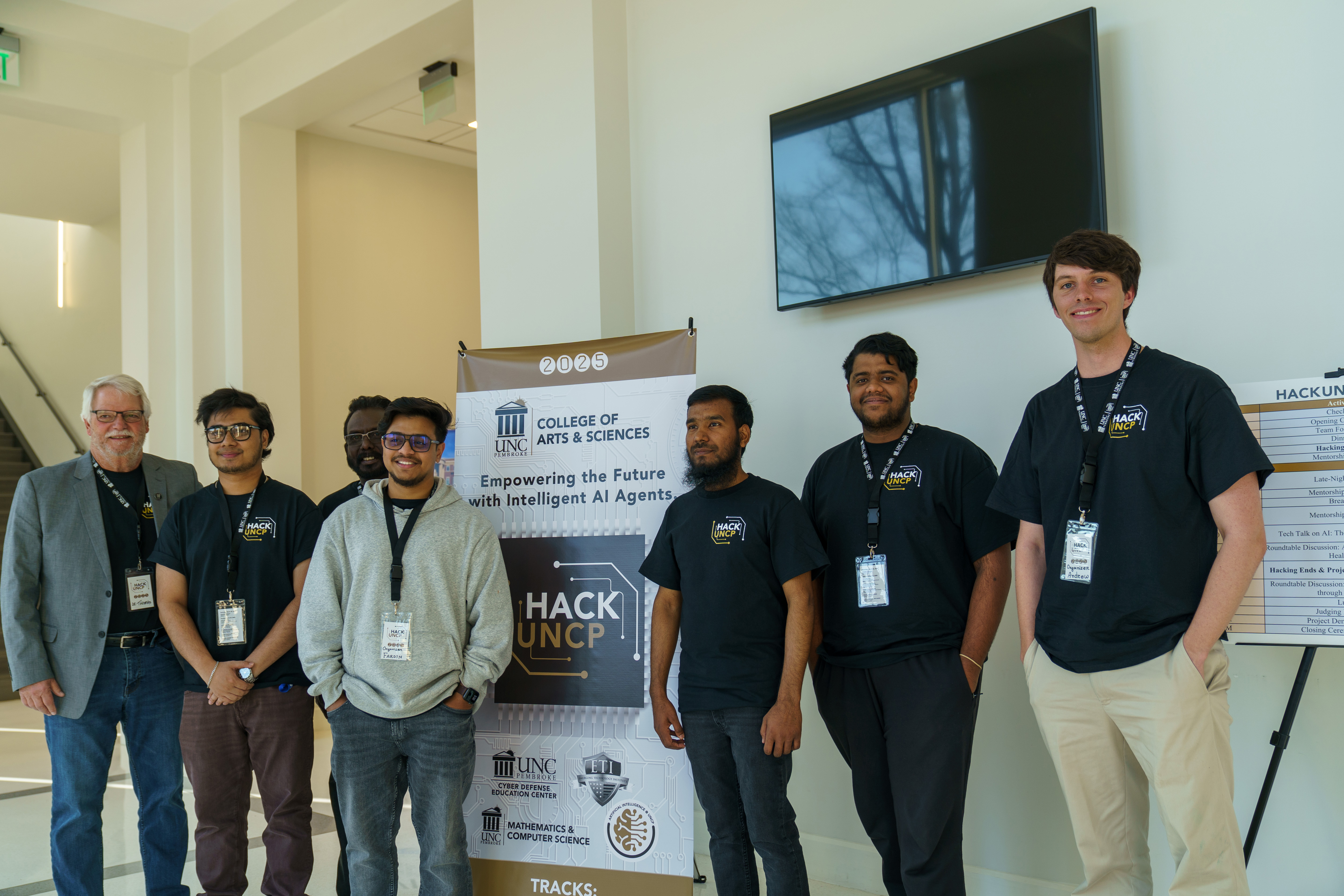 group of students and faculty stand with Hack UNCP sign