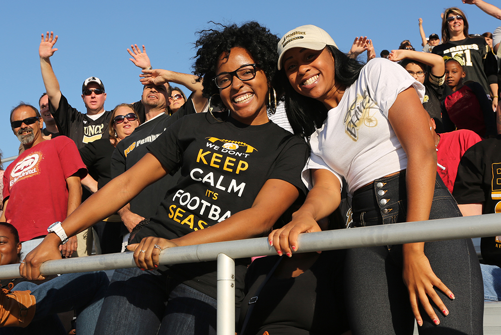 two UNCP alum cheering at a football game