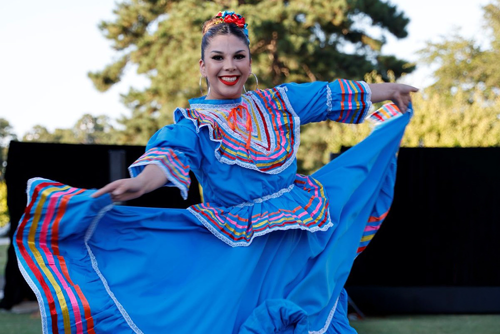 Hispanic student in traditional garb dancing, mid- spin at UNC Pembroke.