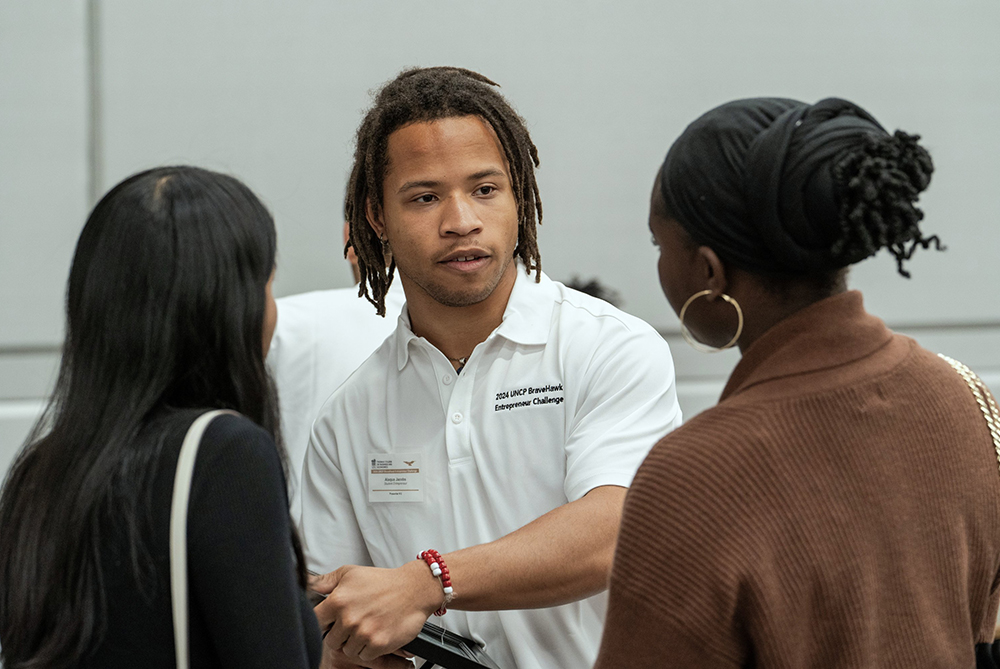 Male SGA member at UNC Pembroke talking with two female students.