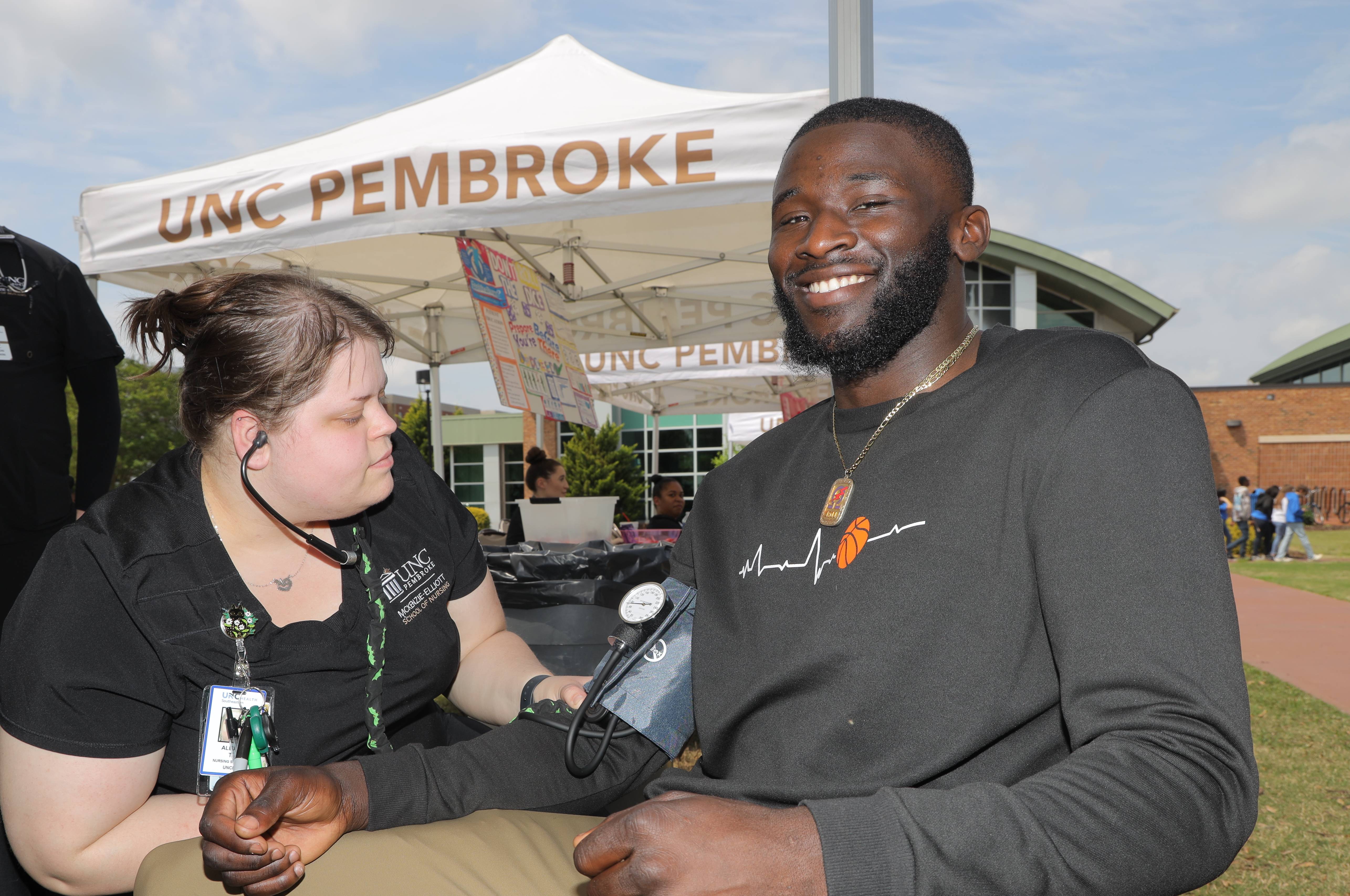 UNCP nursing student checking blood pressure at the Health and Wellness Fair