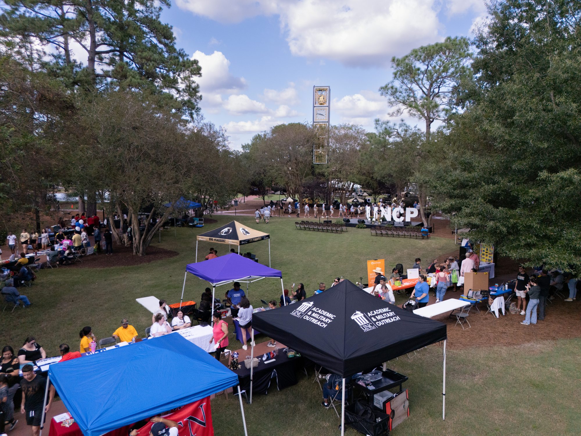 Drone image of the quad and clock tower at UNC Pembroke during Pembroke Day. There are canopies along the walkways for different departments, clubs and organizations.