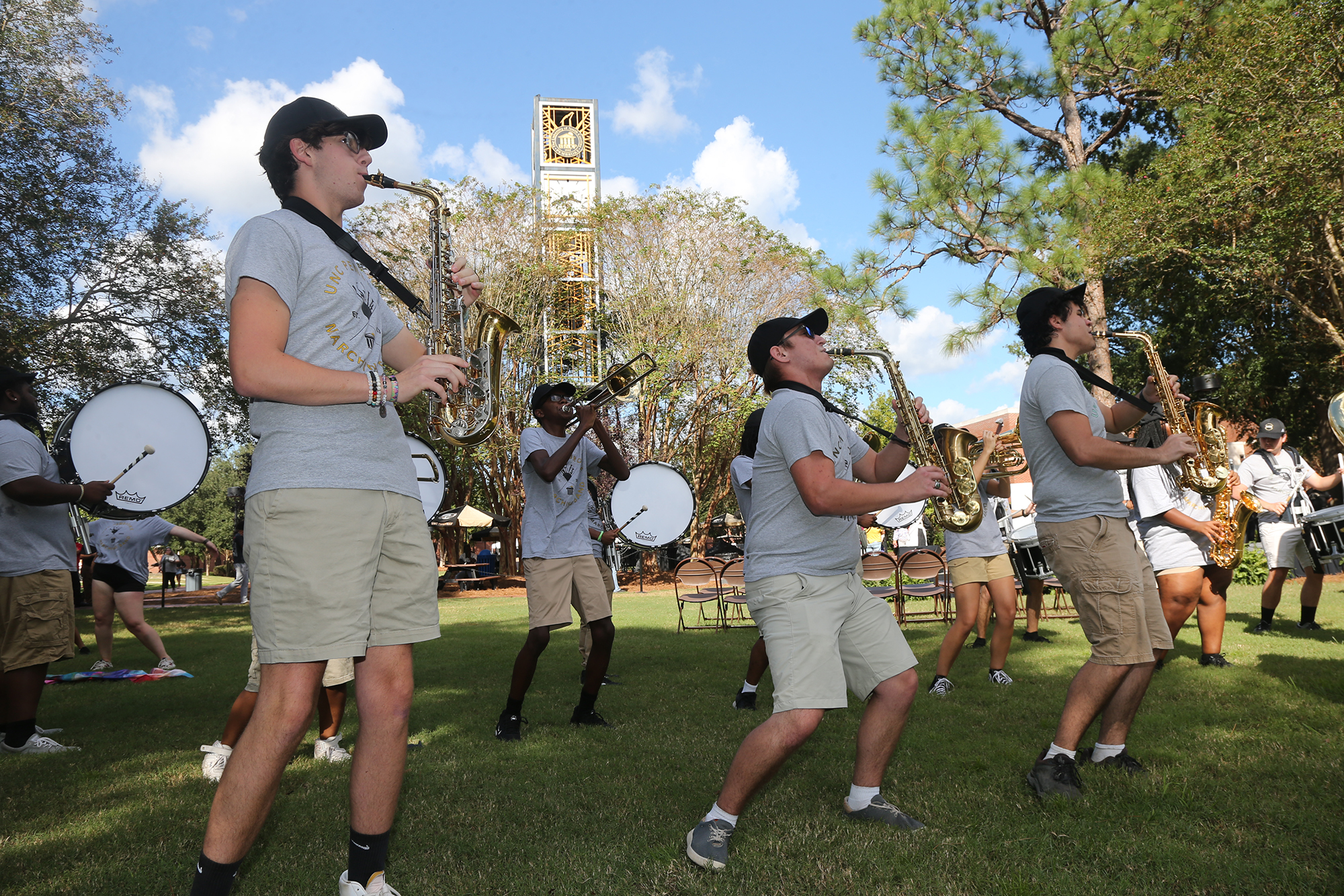 members of UNCP marching band playing instruments with the clocktower in the background