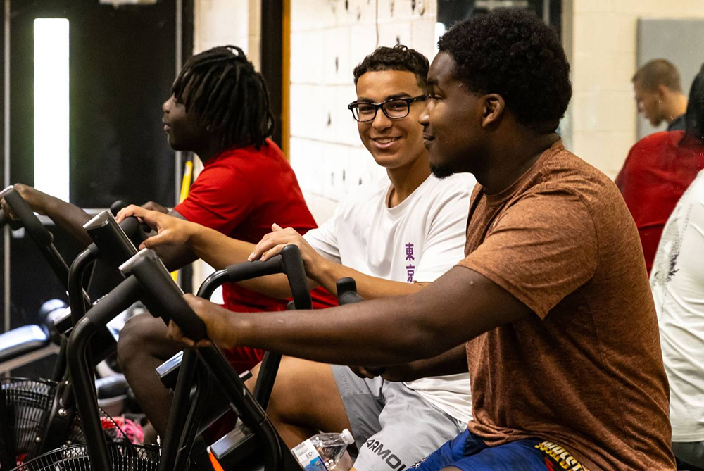 UNCP students on stationary bikes looking at the camera