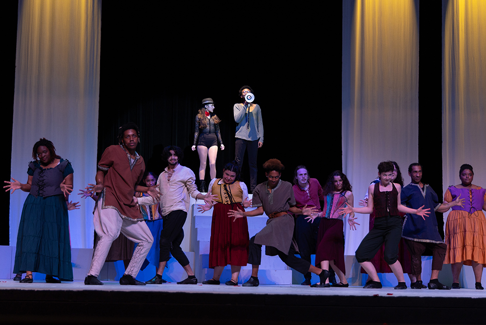 Young performers in colorful costumes act out a royal scene on stage during a theatrical production, showcasing student creativity and engagement in UNC Pembroke's theatre program.