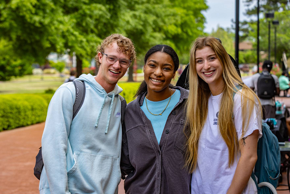 group of students posing in front of a building on campus.