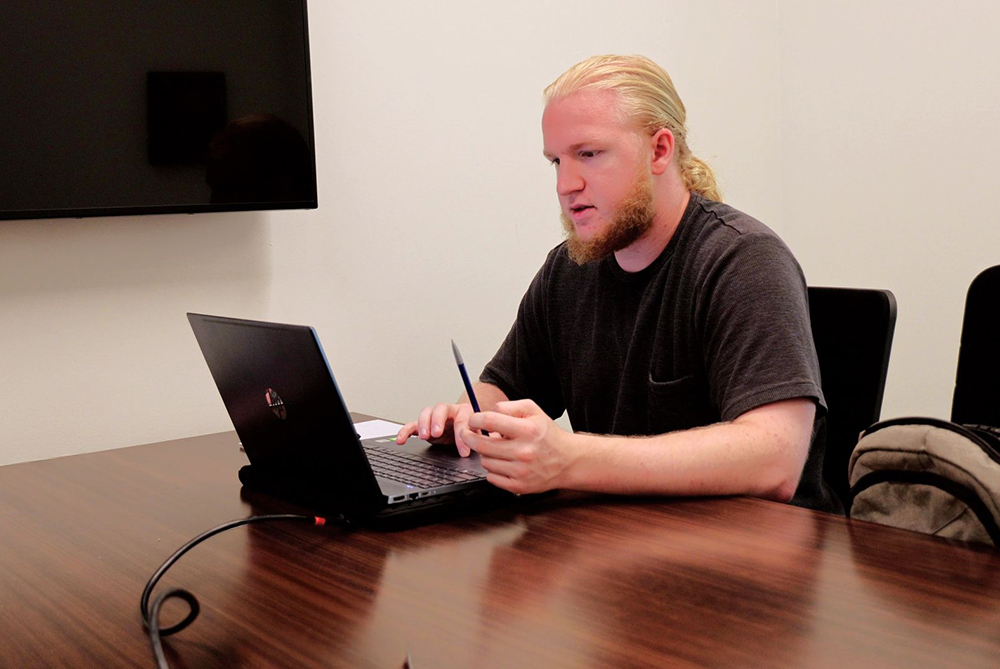 Male UNCP student at his computer in a study room.