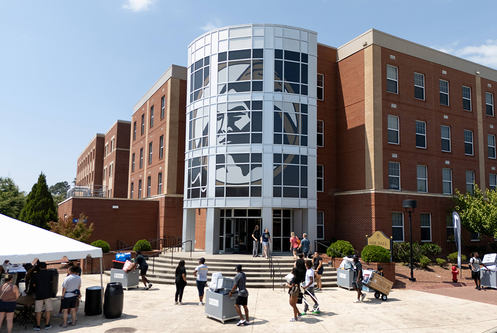 People outside of Oak Hall on Move-In day with lots of boxes and bags