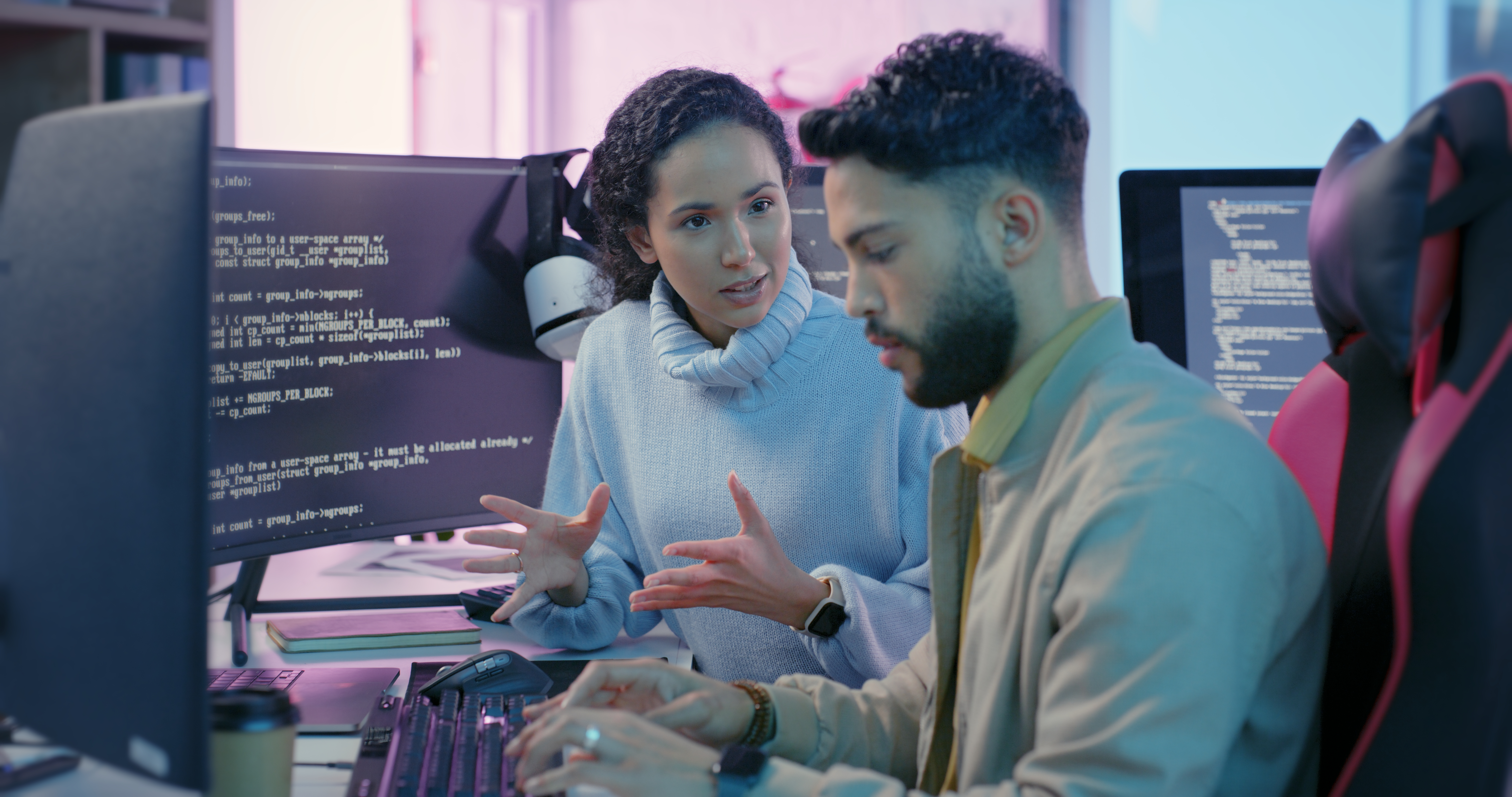 man and woman talk at computer screens