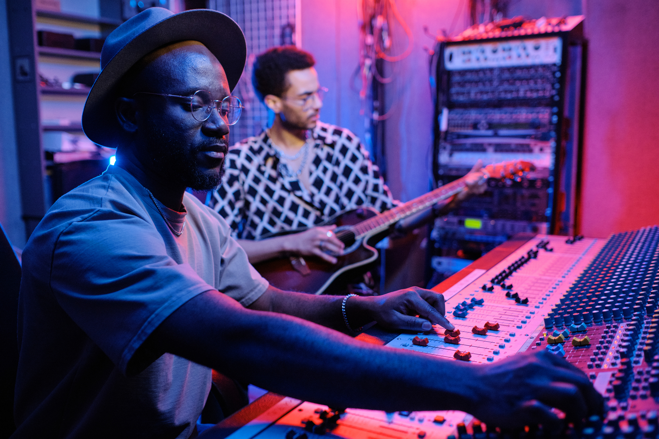 Male at a sound board and a guitar player in the background