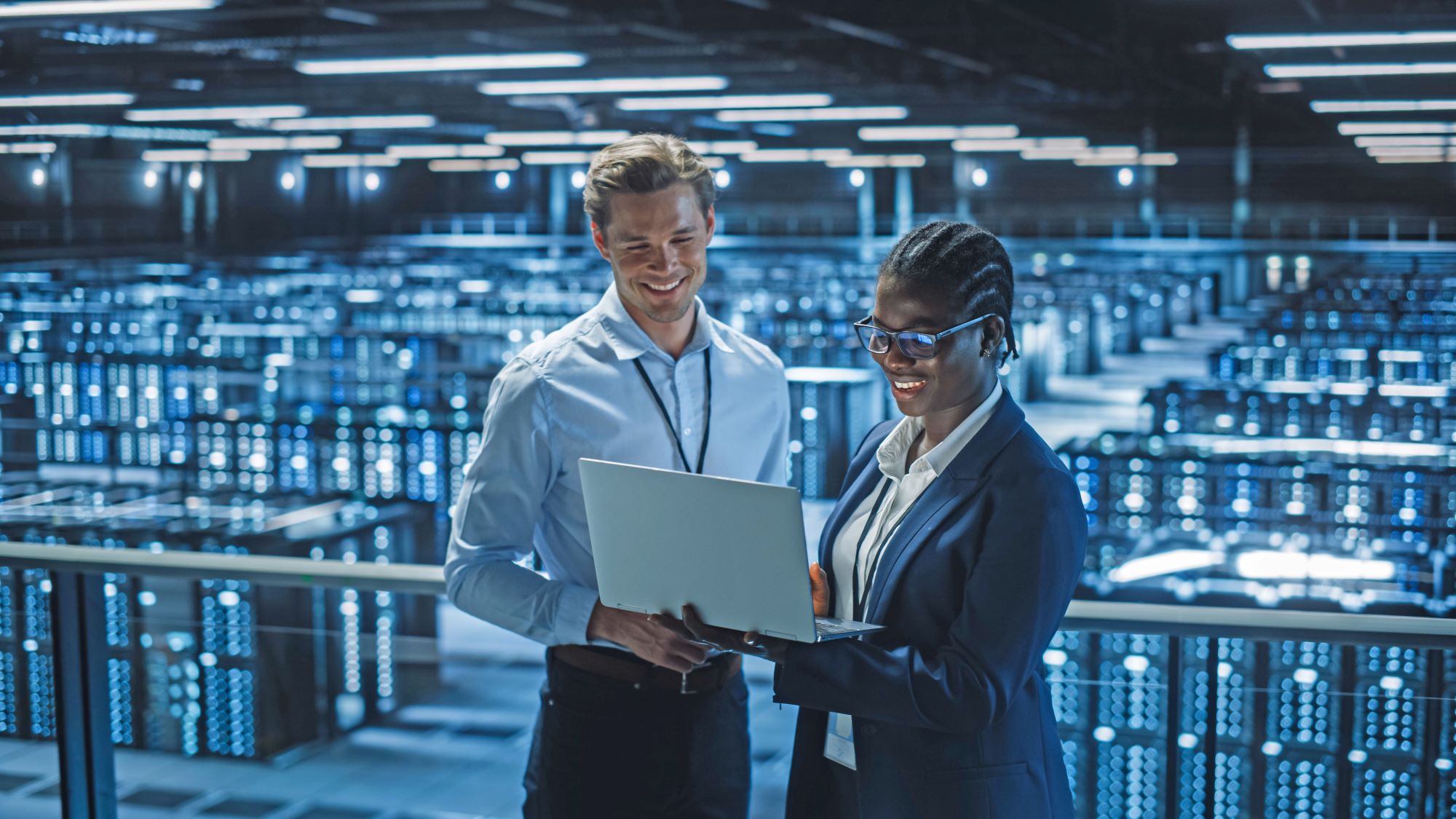 IT people standing with a laptop in front of a data room