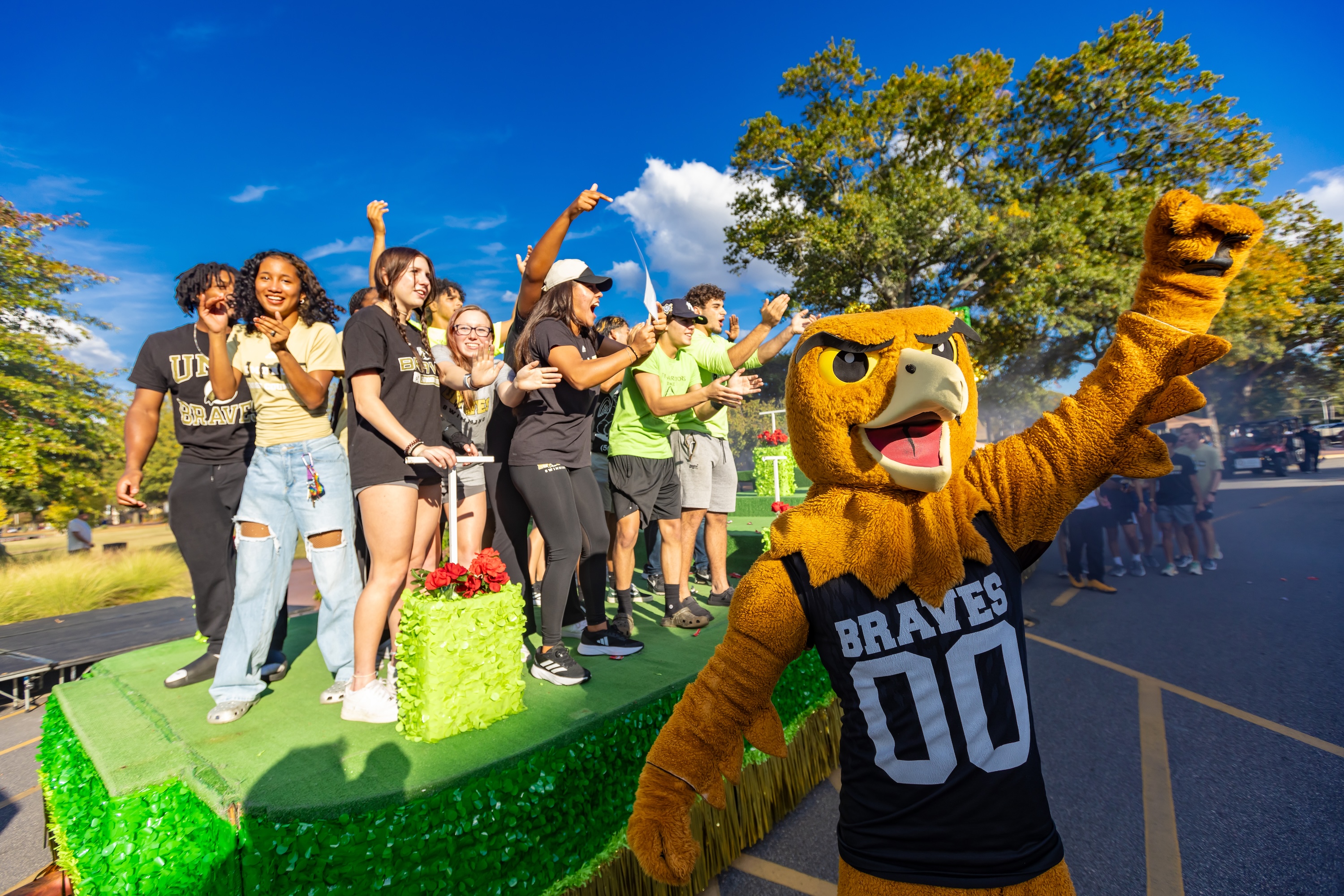 UNCP students and BraveHawk mascot on a float at homecoming