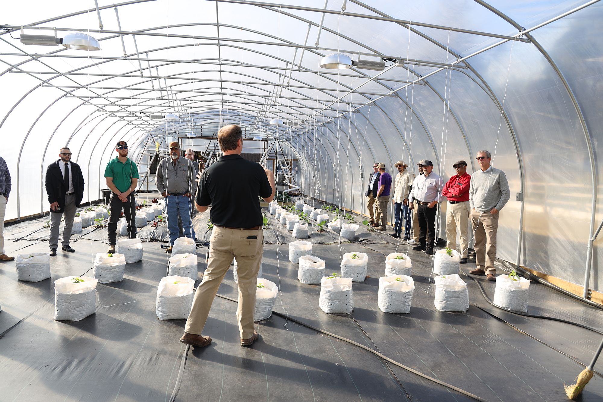 Dr. Bryan Sales speaks to a group inside the greenhouse