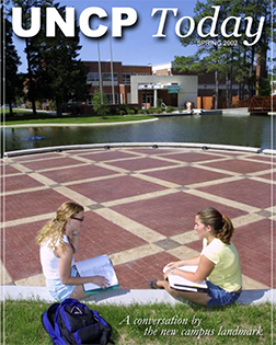 two students sitting in front of the new water feature from the cover of the UNCP Today spring 2002 edition