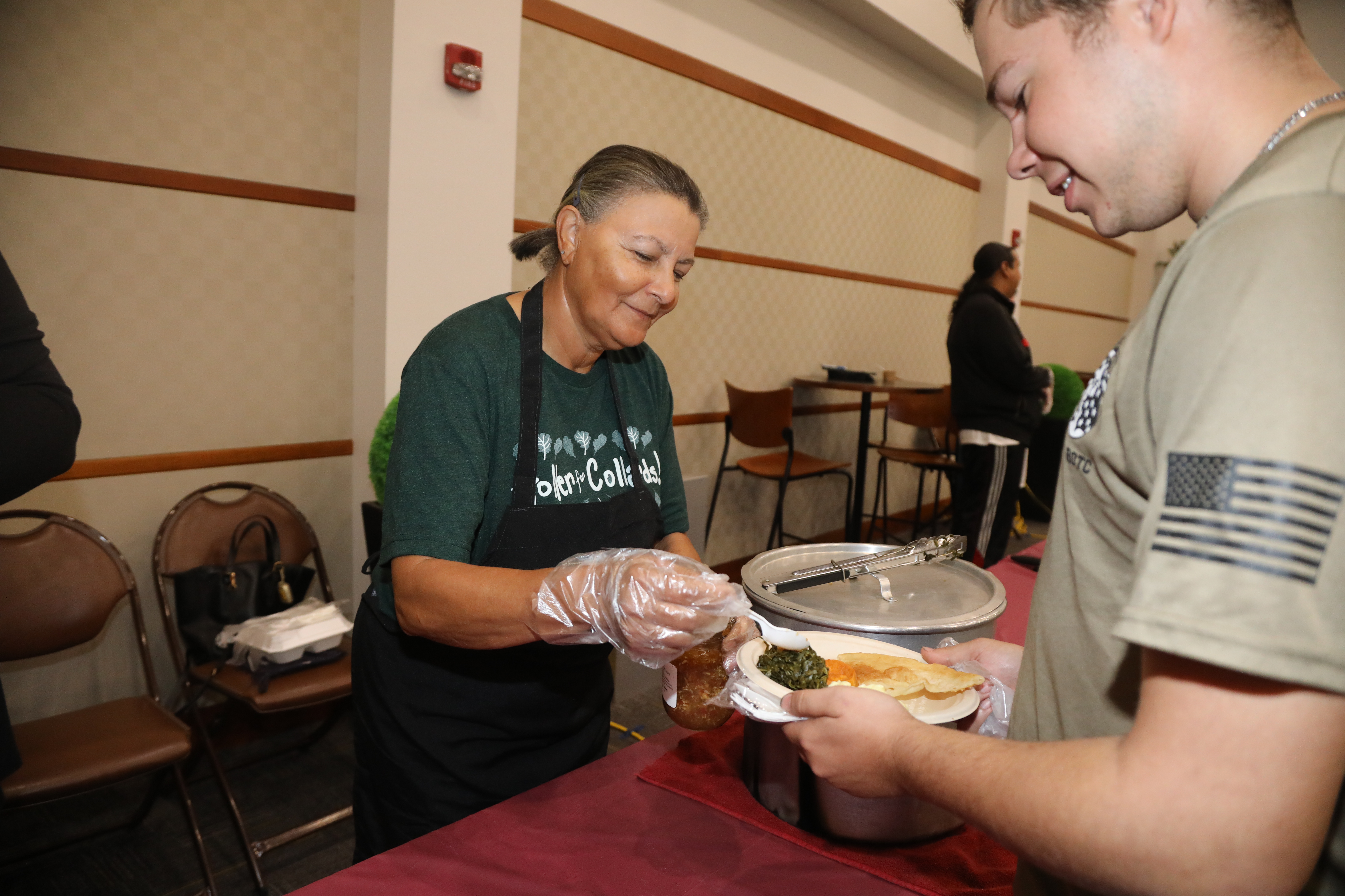 male student with plate of food being served by American Indian woman
