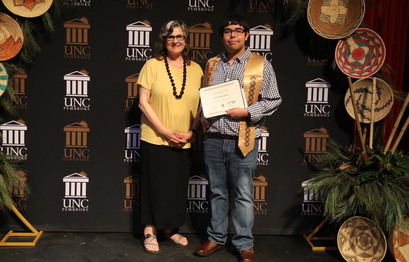 Dr. Mary Jacobs stands with AIS student Seth Oxendine during an event