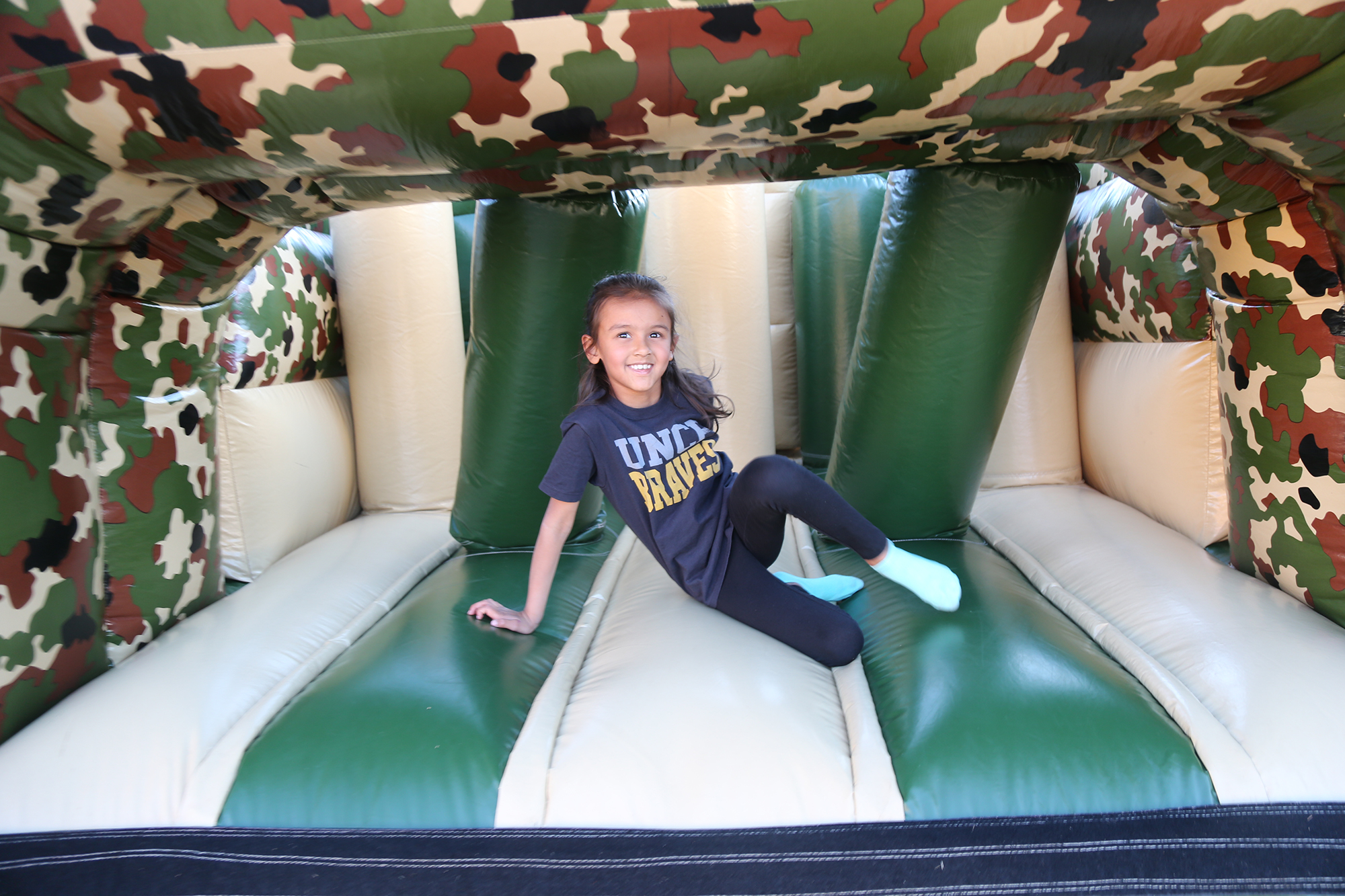 Child wearing UNC Pembroke shirt playing on an inflatable slide
