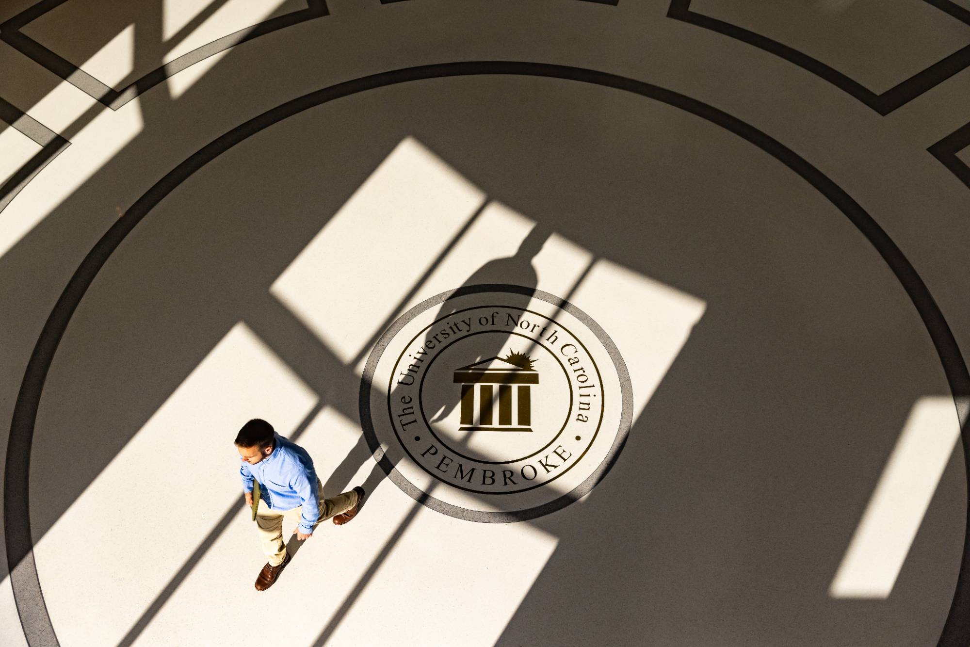 man walking across floor with UNCP logo