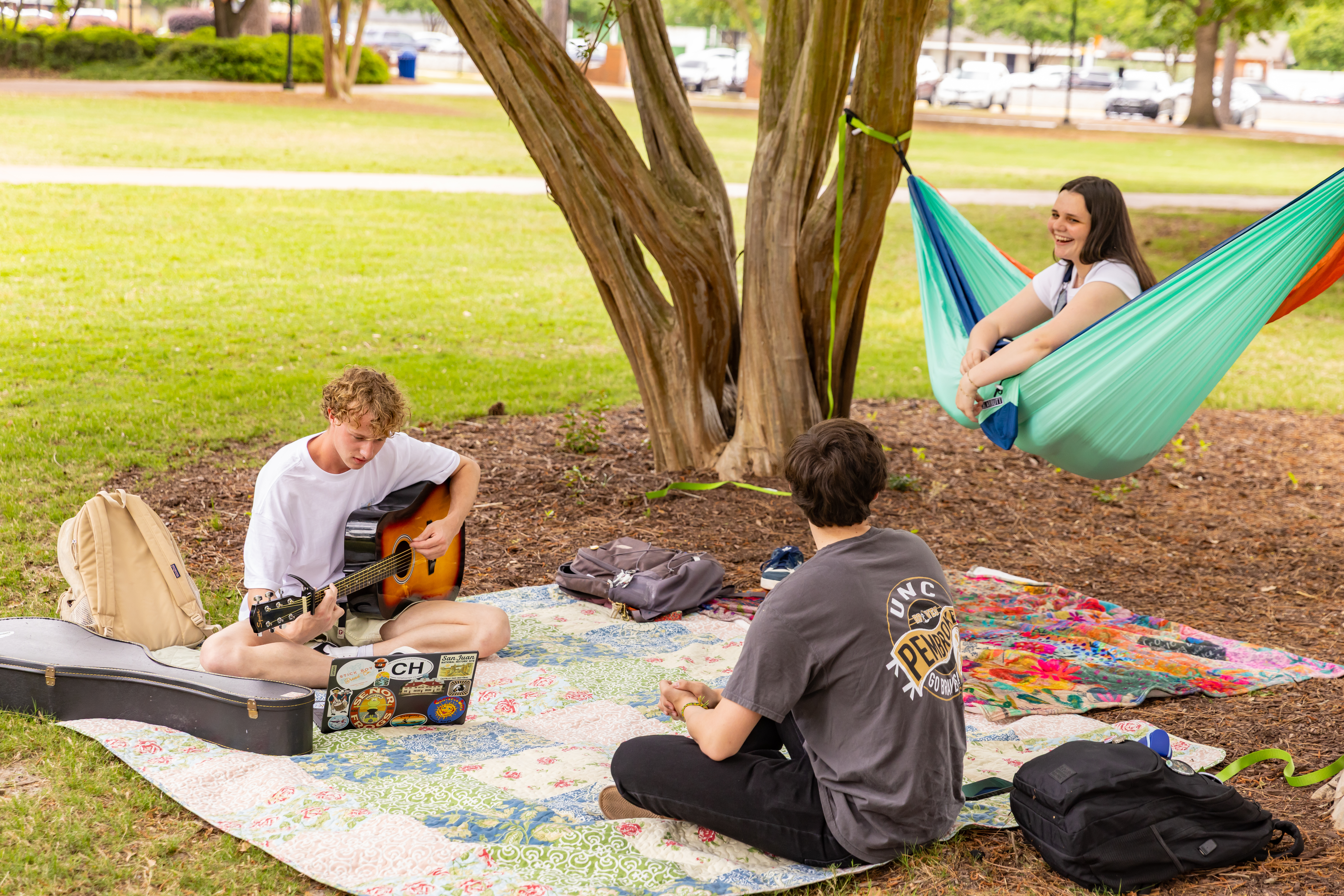 students on campus playing guitar hammock blanket