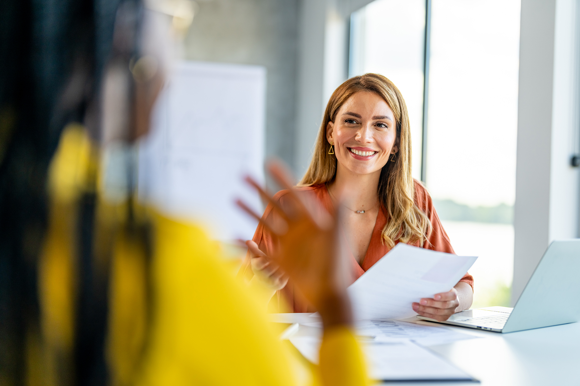 smiling woman helping another woman filling out an application