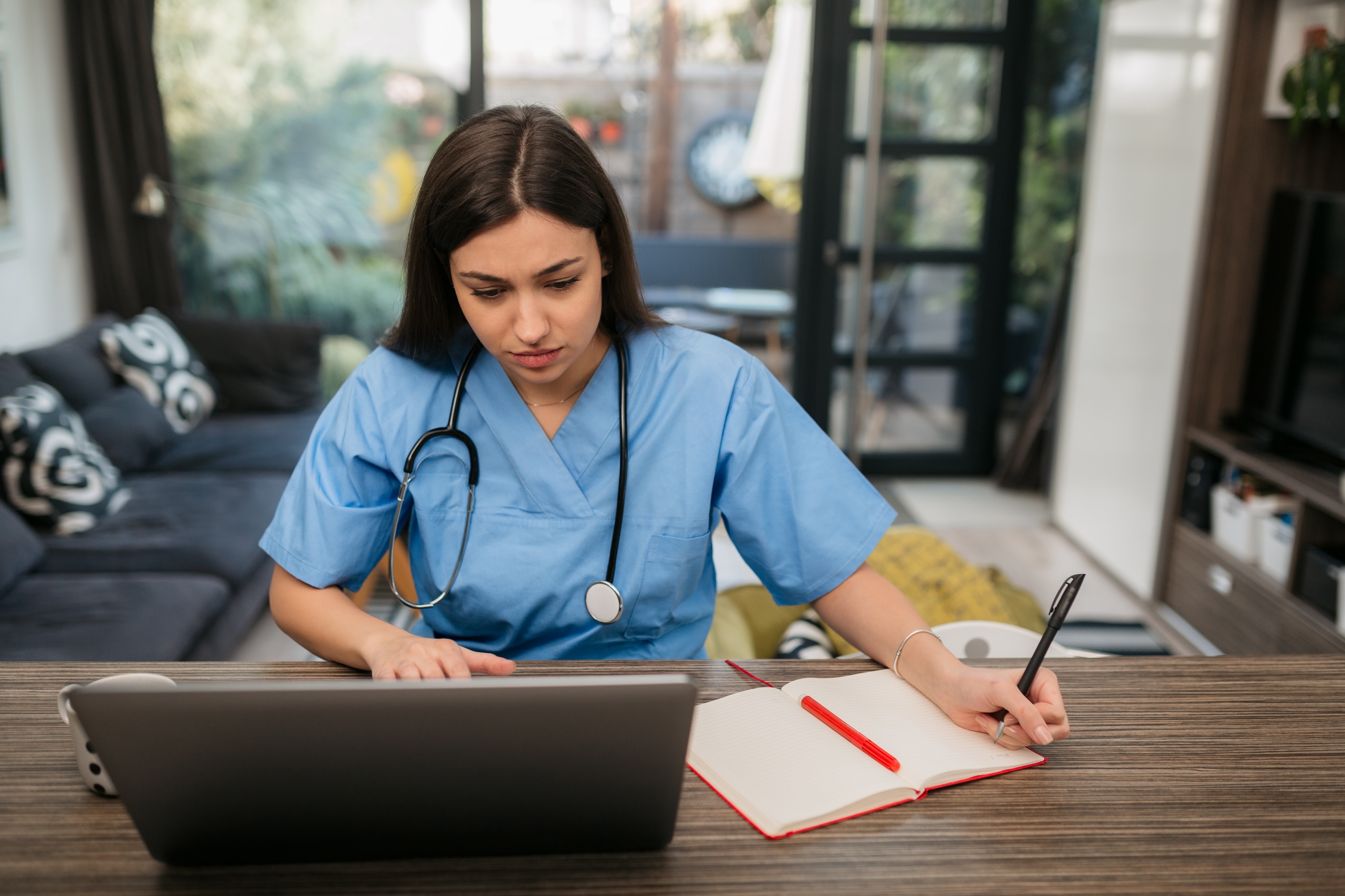 Woman in scrubs working on a laptop