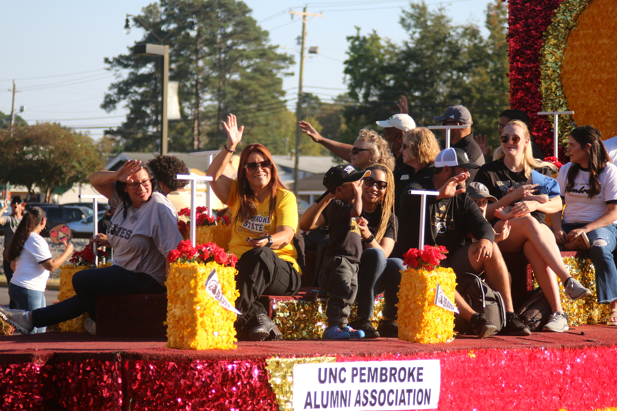 UNC Pembroke alumni association members ride a float in the homecoming parade